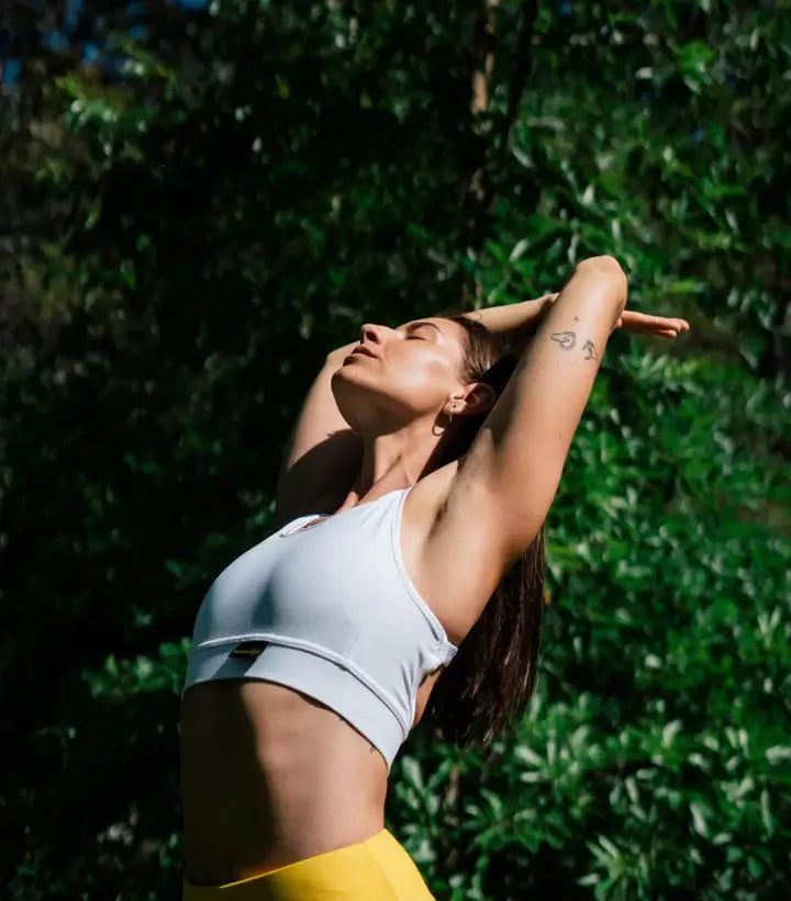 Woman stretching outdoors in fitness attire, promoting health and wellness in a natural setting.
